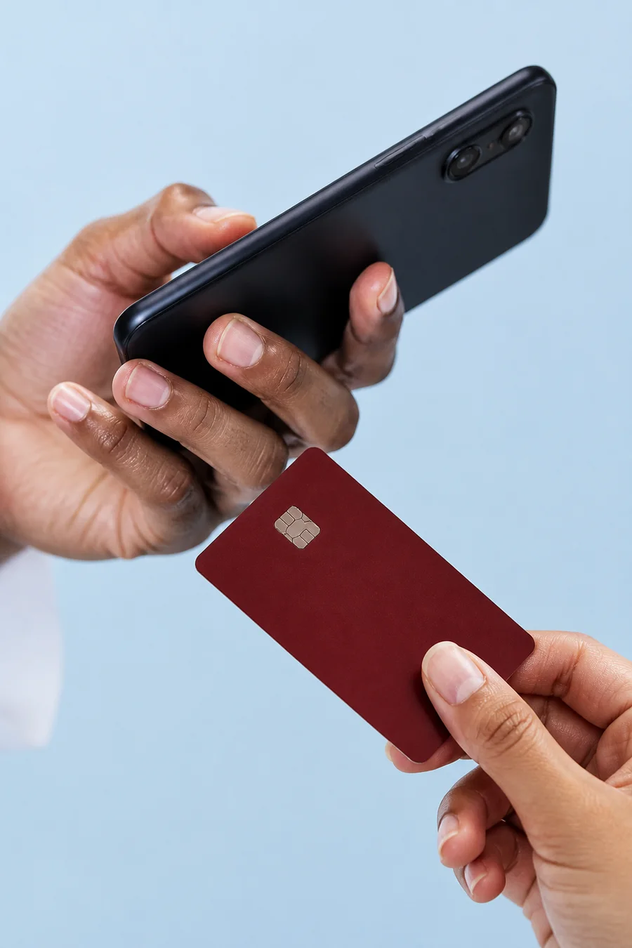 A person holding a payment card beside a mobile phone